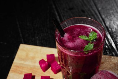 Fantastik kalın kırmızı suyu yanan ahşap arka plan üzerinde geniş bir bardak. Dekoratif nane ile pancar güler yüzlü bırakır. Koyu pembe pancar küpleri besleyici bir salata için kesti. Serinletici içecekler.