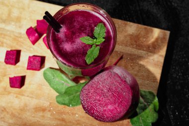 Yukarıdan bir cam ile pancar içecek nane, şeker ve payet, ham, kıyılmış yarım kırmızı pancar, mükemmel pancar küpleri ve bir masa siyah zemin üzerine yeşil yaprakları ile renkli bir dizi görüntüleyin.