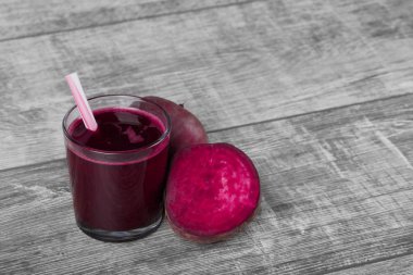 Renkli pancar bir cam ahşap masa arka plan üzerinde küçük bir saman ile harmanlanmış. Bir içki yanında parlak kırmızı pancar yarısı. Besleyici tarım malzemeleri. Uzay kopyalayın. Yaz konsepti.