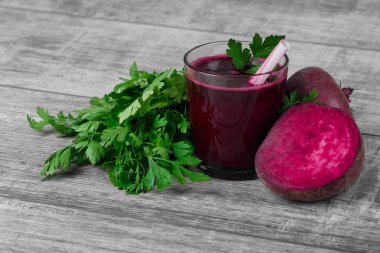 Doymuş kırmızı pancar bir ışık ahşap Resepsiyon arka plan üzerinde kokteyl süslü bir bardak. Bir dilimlenmiş yarım pancar ve taze salata. Bir saman ile ekşi veggie içki. Tarım ve sağlık kavramı.