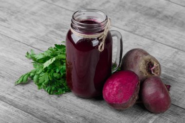 Hafif ahşap arka plan üzerinde kırmızı pancar ürünlerin güzel bir kompozisyon. Besleyici ve sağlıklı pancar rustik maydanoz ile. Tatlı kırmızı pancar içecek bir mason kavanoz. Kopya alanı.