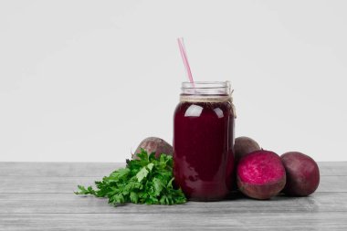 Pancar içecek beyaz bir arka plan üzerinde izole gri bir ahşap masa üzerinde şeffaf bir kavanoz. Birtakım sağlıklı sebze ve Yeşiller. Kıyılmış beetroots ve ferahlatıcı salata. Kopya alanı