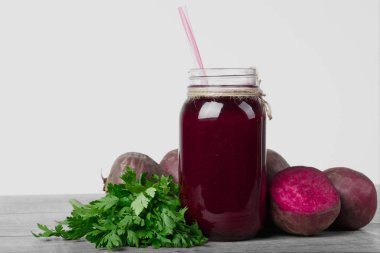 Pancar içecek beyaz bir arka plan üzerinde izole gri bir ahşap masa üzerinde şeffaf bir kavanoz. Birtakım sağlıklı sebze ve Yeşiller. Kıyılmış beetroots ve ferahlatıcı salata. Kopya alanı
