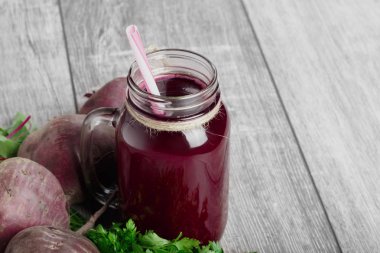 Hafif ahşap arka plan üzerinde uzun boylu, büyük cam şişede taze pancar iç. Bütün beetroots vitamin tam ve sağlıklı yeşil salata için bırakır. Sağlıklı kahvaltı için malzemeler.