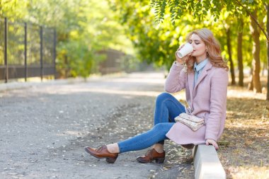 Güzel sarışın Kaldırıma park kahve ile oturuyor.