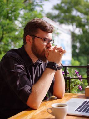 Bir genç sakallı adam onun laptop kullanarak bir kafede oturuyor.