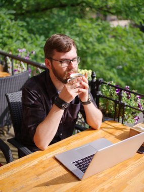 Bir genç sakallı adam onun laptop kullanarak bir kafede oturuyor.