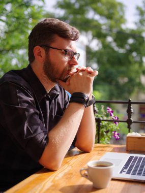 Bir genç sakallı adam onun laptop kullanarak bir kafede oturuyor.