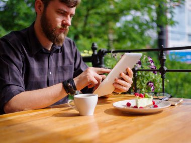 Bir genç sakallı adam onun laptop kullanarak bir kafede oturuyor.