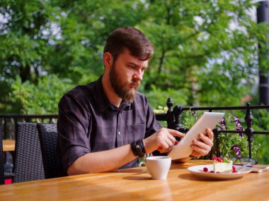 Bir genç sakallı adam onun laptop kullanarak bir kafede oturuyor.