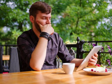 Bir genç sakallı adam onun laptop kullanarak bir kafede oturuyor.