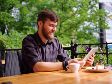 Bir genç sakallı adam onun laptop kullanarak bir kafede oturuyor.