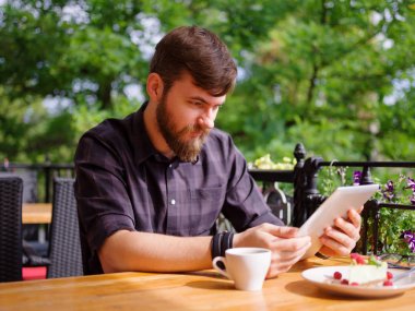 Bir genç sakallı adam onun laptop kullanarak bir kafede oturuyor.
