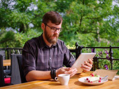 Bir genç sakallı adam onun laptop kullanarak bir kafede oturuyor.
