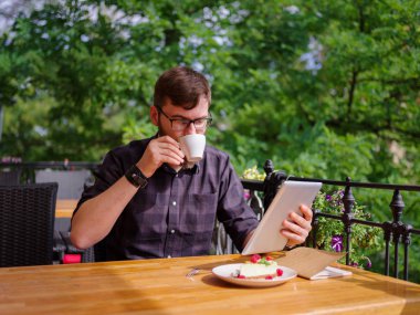 Bir genç sakallı adam onun laptop kullanarak bir kafede oturuyor.