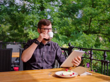 Bir genç sakallı adam onun laptop kullanarak bir kafede oturuyor.