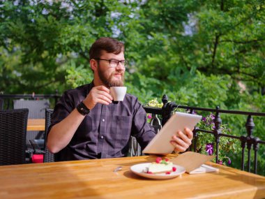 Bir genç sakallı adam onun laptop kullanarak bir kafede oturuyor.