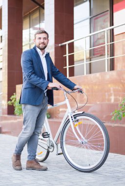 Şehir arka plan üzerinde bir bisiklet ile olumlu iş adamı. Eko taşıma kavramı. Kopya alanı.