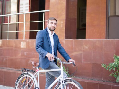 Şehir arka plan üzerinde bir bisiklet ile olumlu iş adamı. Eko taşıma kavramı. Kopya alanı.