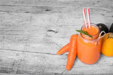 Bir mason kavanoza Detoks havuç içecek ve doğal maddeler üstten görünüm gri ahşap masa arka plan üzerinde. Portakal suyu soyulmuş havucu tüpler grubunun yanındaki büyük bir mason kavanoza. Kopya alanı.