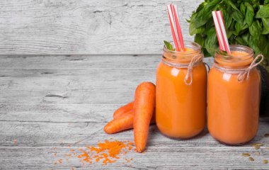 Mason kavanoza gri ahşap masa arka plan üzerinde sağlıklı havuç içecek dolu. 