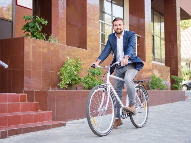 İşadamı caddeden aşağı beyaz bisiklet sürme