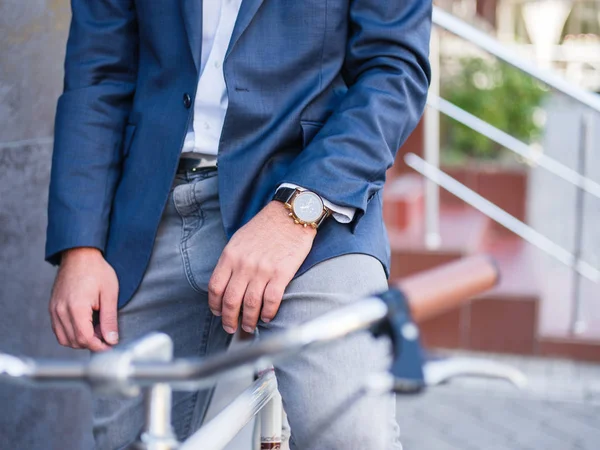 Businessman on a bicycle close-up with a expensive clock