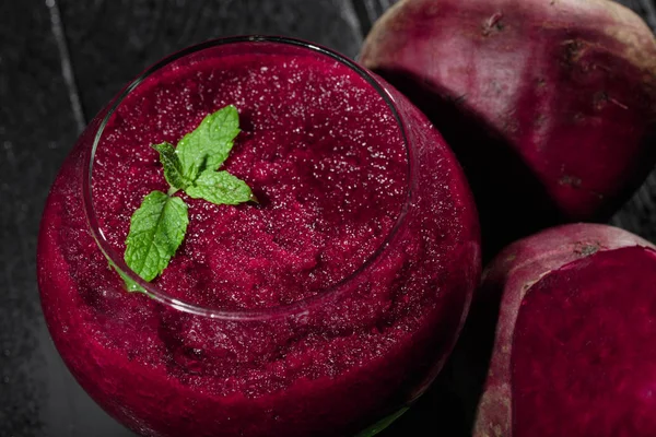 Parlak kırmızı pancar güler yüzlü bir cam siyah tablo arka plan üzerinde bir yakın çekim resim. Sulu beetroots taze salata yaprakları ve yeşil dekoratif nane ile. Detoksifikasyon ve diyet kavramı.