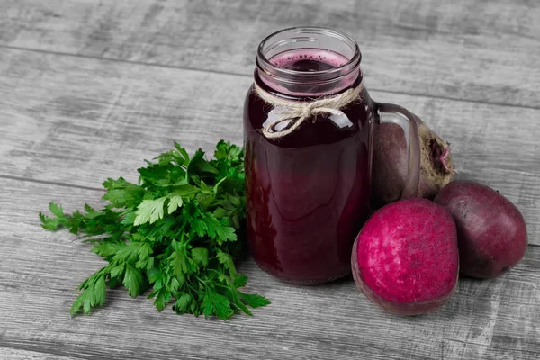 A beautiful composition of beetroot products on a light wooden background. Nutritious and healthful beets with rustic parsley. A mason jar of sweet beetroot beverage. Copy space.