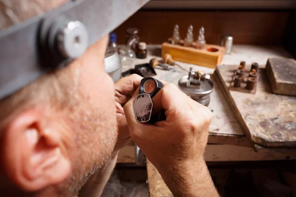 Un joyero de cerca trabajando. Artesano haciendo joyas en un fondo de taller. Concepto de fabricación de accesorios . — Foto de Stock