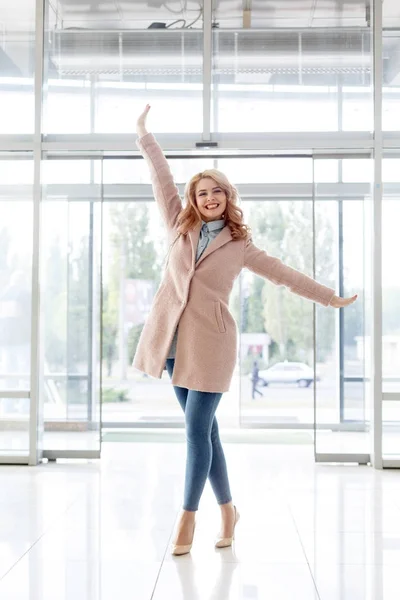 Menina loira bonita em um belo casaco bege, jeans e salto alto . — Fotografia de Stock