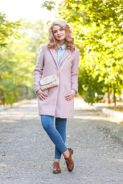 Portret młodej dziewczyny piękne w różowy płaszcz. W parku. — Zdjęcie stockowe