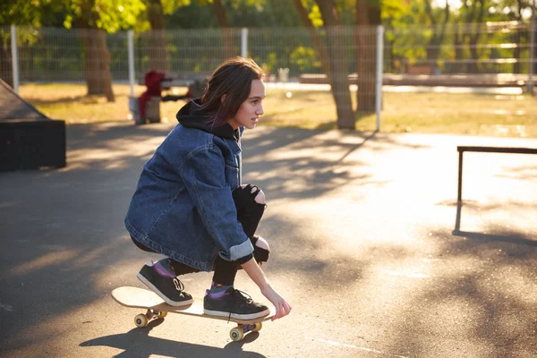 Kaykay üzerinde oturan genç kız. Kaykay. Açık havada, yaşam biçimi.