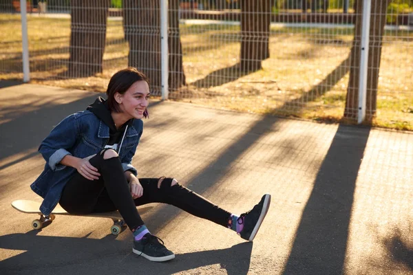 Девушка сидит на скейтборде в парке . — стоковое фото