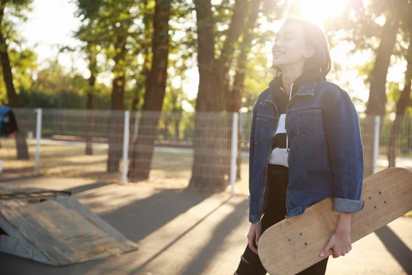 Bir kot ceket bir kaykay ile genç bir kız duruyor