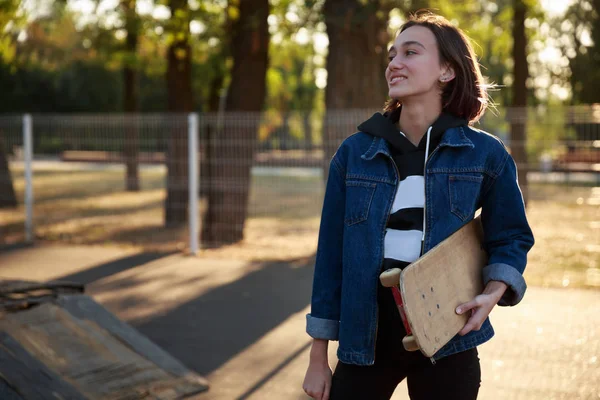 Bir kot ceket bir kaykay ile genç bir kız duruyor