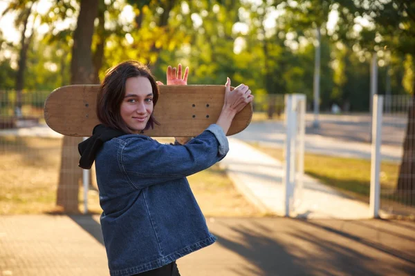Bir kot ceket bir kaykay ile genç bir kız duruyor
