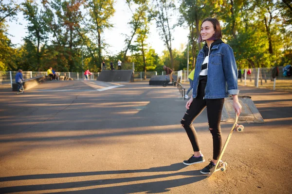 Bir kot ceket bir kaykay ile genç bir kız duruyor