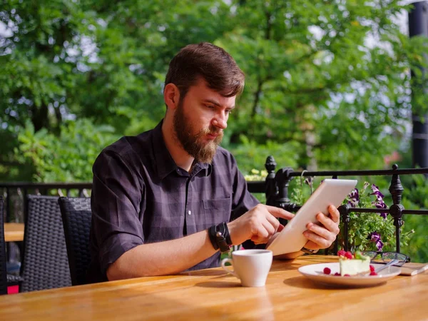Bir genç sakallı adam onun laptop kullanarak bir kafede oturuyor.