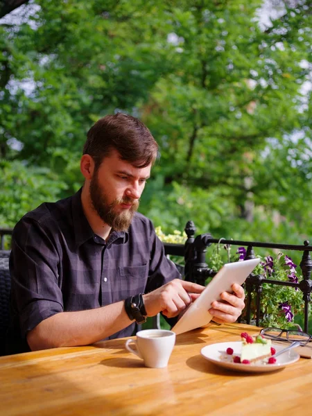 Bir genç sakallı adam onun laptop kullanarak bir kafede oturuyor.