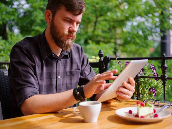 Bir genç sakallı adam onun laptop kullanarak bir kafede oturuyor.