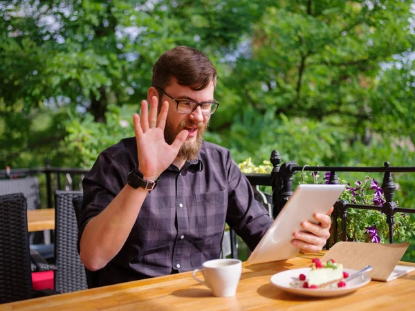 Bir genç sakallı adam onun laptop kullanarak bir kafede oturuyor.
