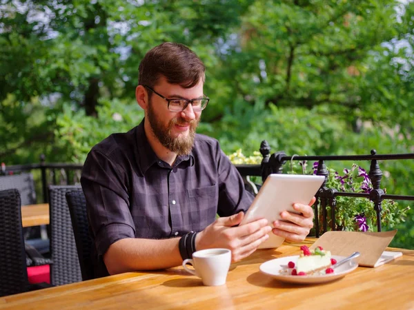 Bir genç sakallı adam onun laptop kullanarak bir kafede oturuyor.