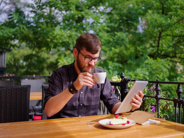 Bir genç sakallı adam onun laptop kullanarak bir kafede oturuyor.