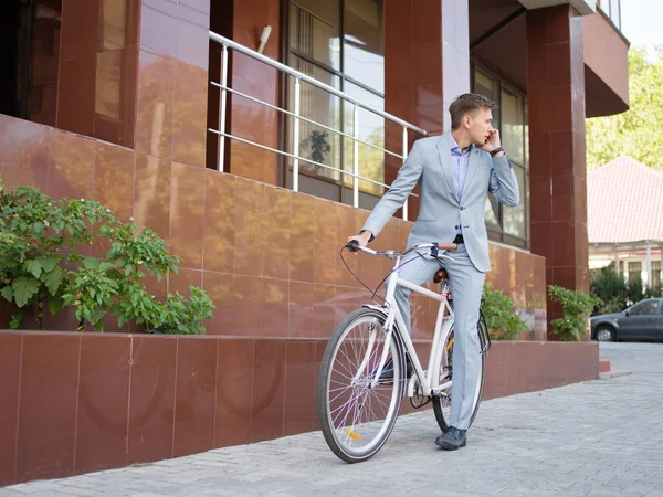 Hombre de negocios guapo montando una bicicleta en el fondo urbano. Concepto de estilo de vida saludable. Copiar espacio . — Foto de Stock