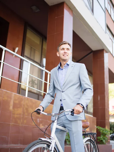 Hombre de negocios guapo montando una bicicleta en el fondo urbano. Concepto de estilo de vida saludable. Copiar espacio . — Foto de Stock