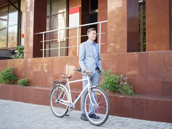 Yakışıklı işadamı kentsel arka plan üzerinde bir bisiklet sürme. Sağlıklı yaşam konsepti. Kopya alanı.