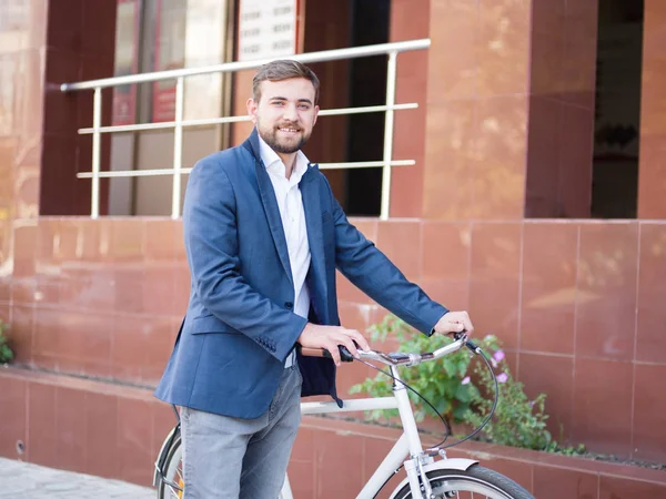 Şehir arka plan üzerinde bir bisiklet ile olumlu iş adamı. Eko taşıma kavramı. Kopya alanı.