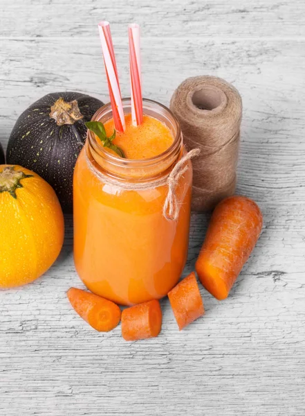 Bir mason kavanoza havuçlu yoğurt, doğal sebze ve gri bir ahşap arka plan iş parçacığında bir bobin üzerinde bir görünüm yukarıdan. Yanında birkaç renkli kabakları ve kesilmiş havuç turuncu içecek.