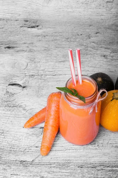 Bir mason kavanoza Detoks havuç içecek ve doğal maddeler üstten görünüm gri ahşap masa arka plan üzerinde. Portakal suyu soyulmuş havucu tüpler grubunun yanındaki büyük bir mason kavanoza. Kopya alanı.